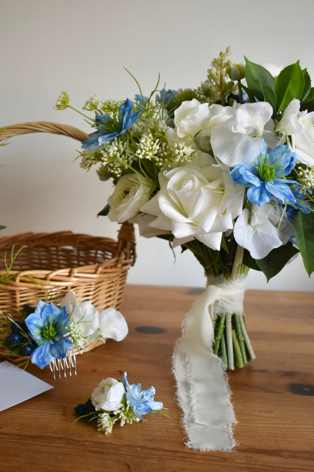 High quality artificial flowers in white, blue and green. Includes a bridal bouquet, hair comb, hair clip and flower girl basket. All items are handcrafted in Derbyshire